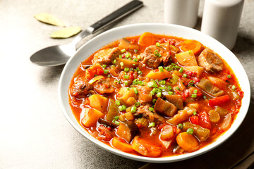 Delicious stew with vegetables in bowl on light grey table, closeup
