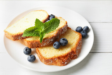 Freshly baked sponge cake, mint and blueberries on white wooden table, closeup