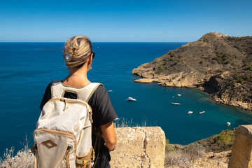 Girl with backpack looking at the sea