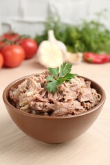 Canned meat with parsley in bowl on wooden table, closeup