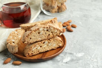 Traditional Italian almond biscuits (Cantucci) and tea on grey textured table, closeup. Space for text