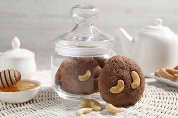 Tasty chocolate cookies with cashew and honey on wicker mat, closeup