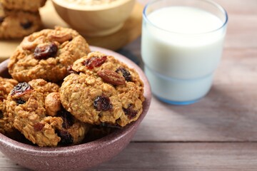 Delicious oatmeal cookies with raisins, nuts and milk on wooden table, closeup