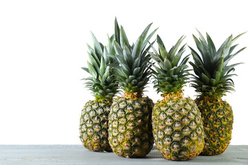 Fresh ripe pineapples on grey table against white background