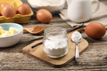 Baking powder in jar and other products on wooden table, closeup
