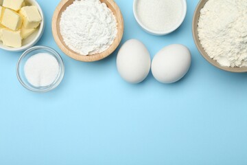 Baking powder and other ingredients for making dough on light blue background, flat lay. Space for text