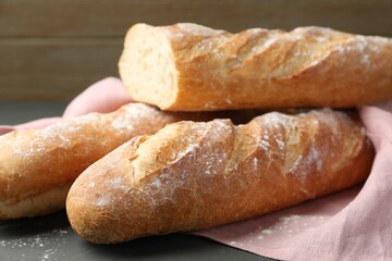Cut fresh baguettes on grey wooden table, closeup