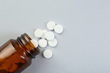 Medical bottle with antibiotic pills on grey background, top view. Space for text