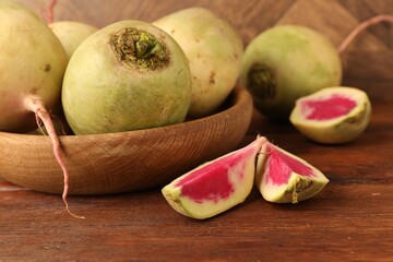 Whole and cut fresh turnips on wooden table, closeup