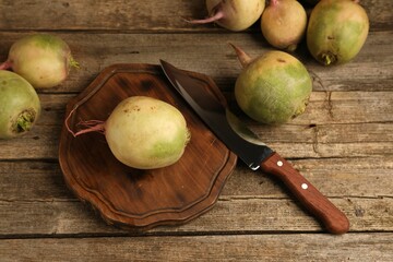 Fresh turnips and knife on wooden table, above view