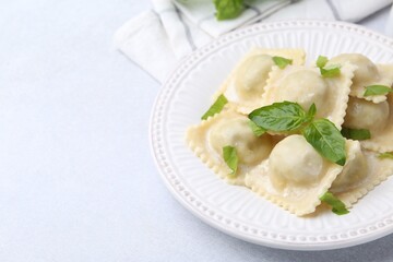 Delicious ravioli with cheese and basil served on light table, closeup. Space for text