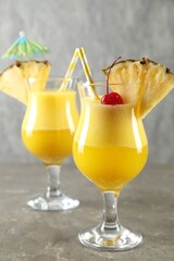 Tasty pineapple cocktail in glasses served on grey table