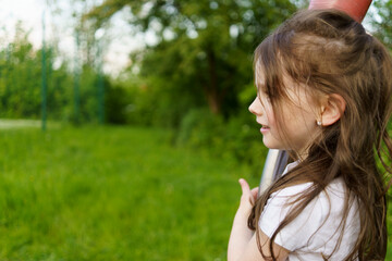 Little cute girl with long hair on playground in summer. Healthy active cheerful child concept