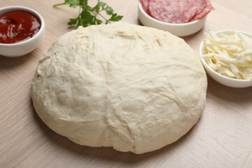 Making calzone pizza. Dough and ingredients on wooden table, closeup
