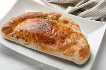Delicious fresh calzone pizza on white wooden table, closeup