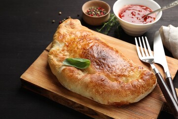 Delicious fresh calzone pizza served on wooden table, closeup