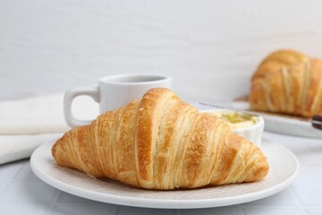 Tasty fresh croissant served on white tiled table, closeup