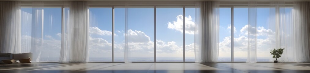 A spacious room with large windows showcasing a bright sky and clouds.