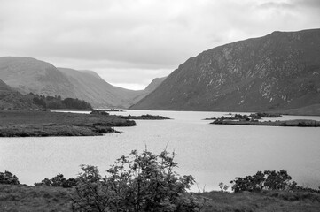 A black and white photo of a lake with mountains in the background