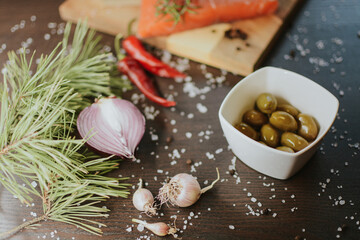 Fresh red salmon on a wooden tray with pepper, salt, garlic, red onion, red pepper, olives with jam