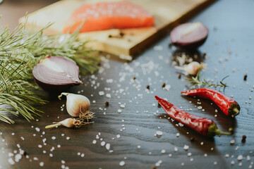 Fresh red salmon on wooden tray with coarse pepper, salt, garlic, red onion, red pepper and rosemary
