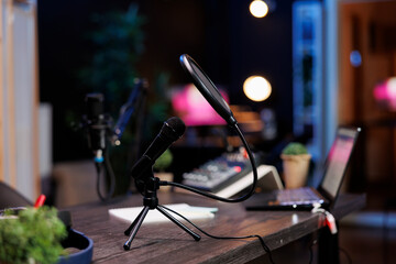 On the table, there is a microphone with a stand and a voice filter for podcasting. Broadcast podcast equipment in the home studio for online live streaming.