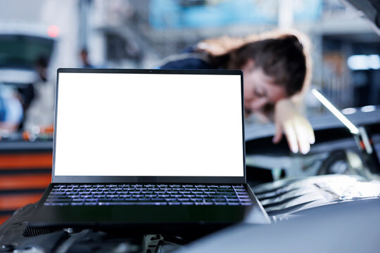 Mockup laptop with blurry background of repairman changing old car brake fluid with new one in repair shop. Isolated screen device and adept garage worker using equipment to do automobile checkup