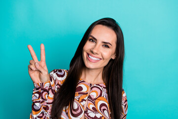 Fototapeta premium Photo of adorable lovely girl wear print shirt showing v-sign empty space isolated turquoise color background