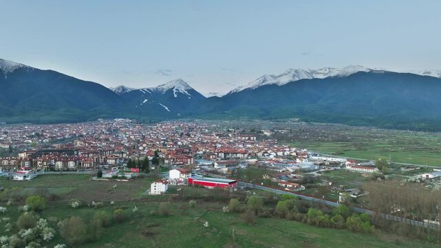 Bansko drone video, orbiting the Southern outskirts of the ski resort town in early April at dawn. 