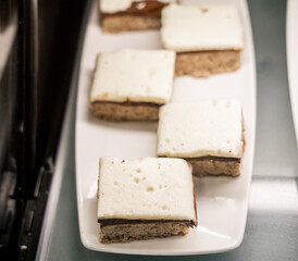 dessert bars topped with marshmallow frosting and a chocolate layer, served on a white plate