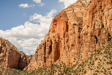 A stunning view of majestic red sandstone cliffs rising in a desert canyon under a blue sky,...