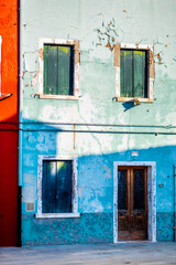 Colorful Weathered Building Facade in Venice with Peeling Paint and Contrasting Red and Blue Walls Under Bright Sunlight Creating a Rustic Italian Charm