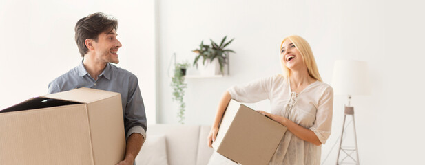 Young Couple Laughing Carrying Packed Boxes With Things Entering New Place. Moving Apartment Concept. Selective Focus