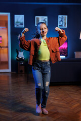 Jolly kid records dance tutorial video in dimly lit apartment for her online audience. Charming...