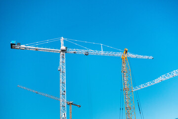 Tower Cranes Against a Clear Blue Sky in a Construction Site