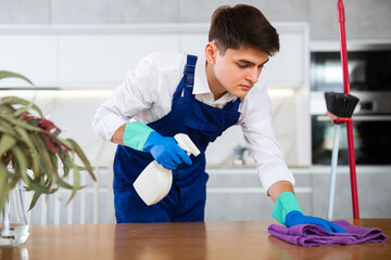 with help of organic detergent, neat young man wipes surface of table