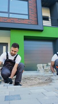 Two diverse construction workers fixing the pavestone on patio