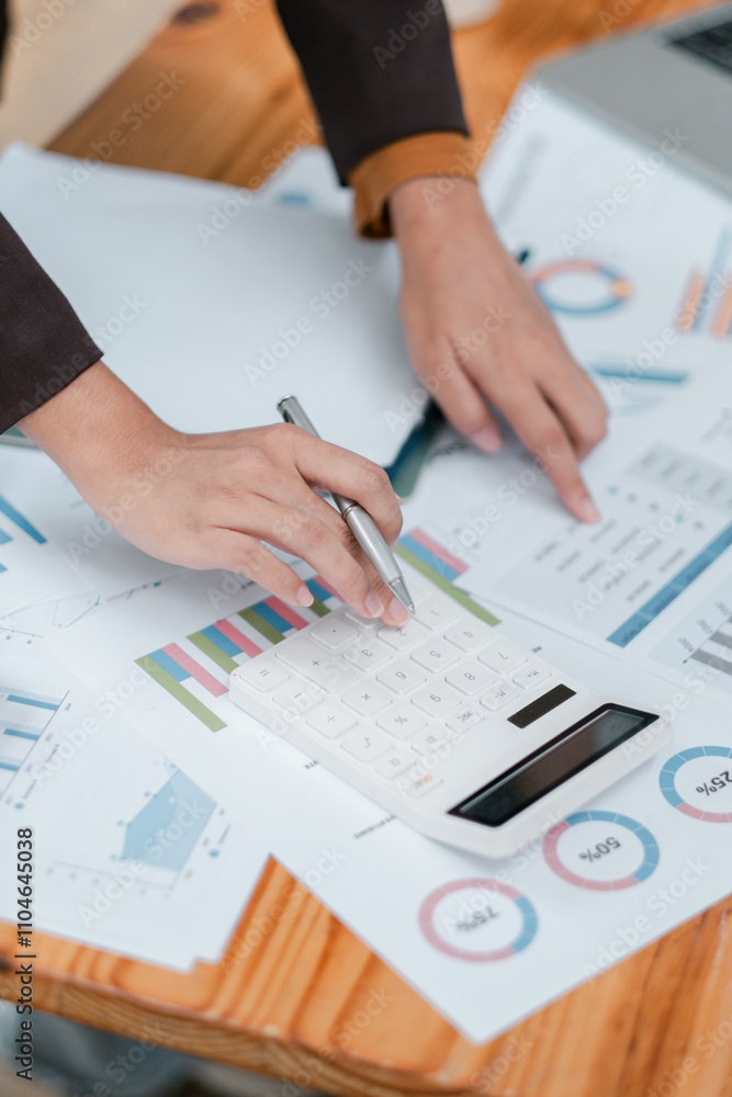 Poster close-up of hands using a calculator on financial charts, showcasing business analysis and data mana