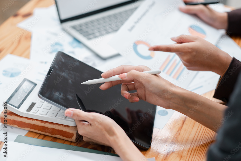 Poster close-up of hands using a tablet and reviewing financial charts, showcasing teamwork and data analys
