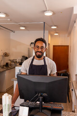 Smiling barista working at coffee shop cash register