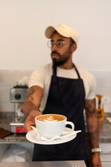 Barista offering a cup of coffee with latte art in a coffee shop