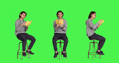 Trendy person reading novel book on chair against full body greenscreen template, enjoying old...