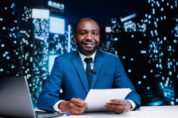 Presenter discussing latest events live on tv channel, reading headlines in news studio and presenting details regarding public interest. Media reporter hosting late night talk show, collecting info.