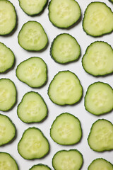 Slices of fresh cucumbers on white background, flat lay