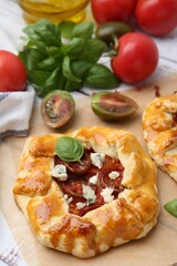 Tasty galettes with tomato, basil and cheese on white wooden table, closeup