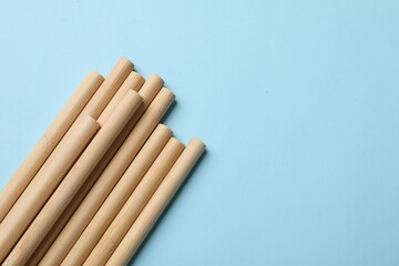 Bamboo drinking straws on light blue background, top view. Space for text
