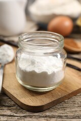Baking powder in jar on wooden table, closeup