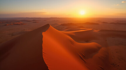 Naklejka premium Experience the breathtaking beauty of the Namib Desert at sunset, where sharp-ridged dunes meet the horizon in a stunning orange glow. 