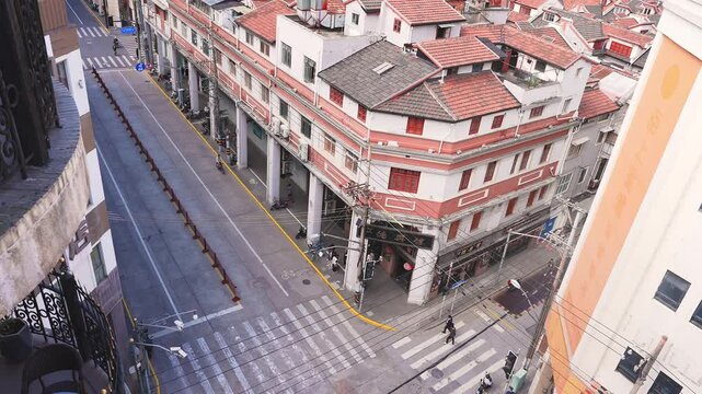 An elevated angle captures a vibrant Shanghai street scene with shikumen buildings, pedestrians, and cars, showcasing the city's dynamic urban life.