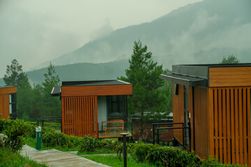 Scenic modern cabins nestled in lush greenery against a dramatic mountain backdrop.